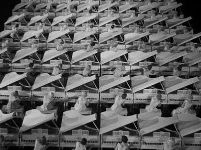 White‑costumed women at white pianos in a black‑background set, resembling a dreamlike rehearsal hal