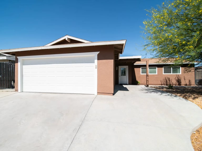 A modern house with a wide concrete driveway.