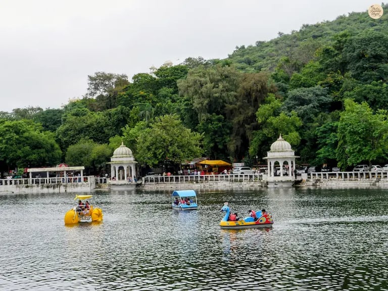 People enjoying boating and water sports at Dudh Talai Lake in Udaipur with surrounding hills in the backdrop.
