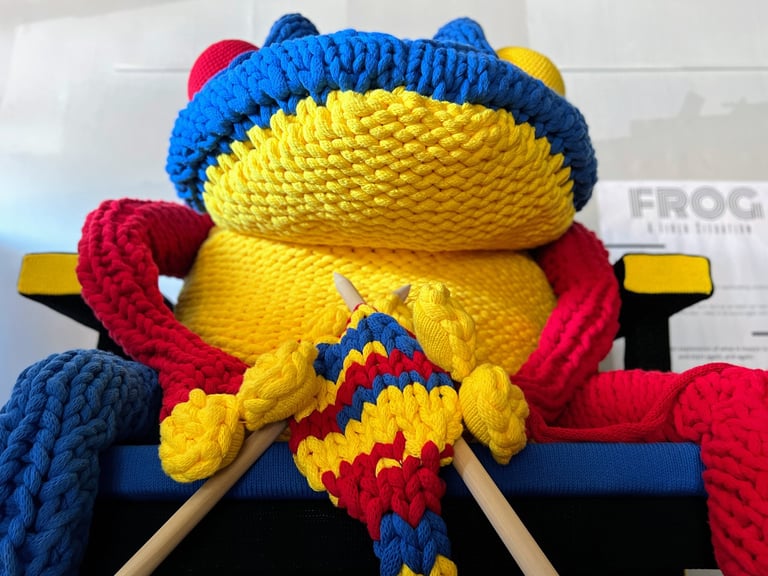 FROG knitting on Rietveld chair with giant knitting needles by Dundee & Lee