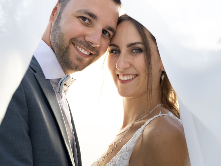 Kreative Hochzeitsfotografie Coburg: Romantisches Brautpaar im Sonnenlicht unter dem Schleier.