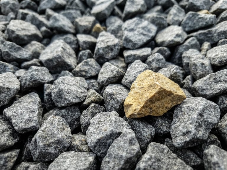 Extreme close-up of sharp, angular 20mm grey aggregate stones, high-contrast natural daylight, gritty industrial texture.