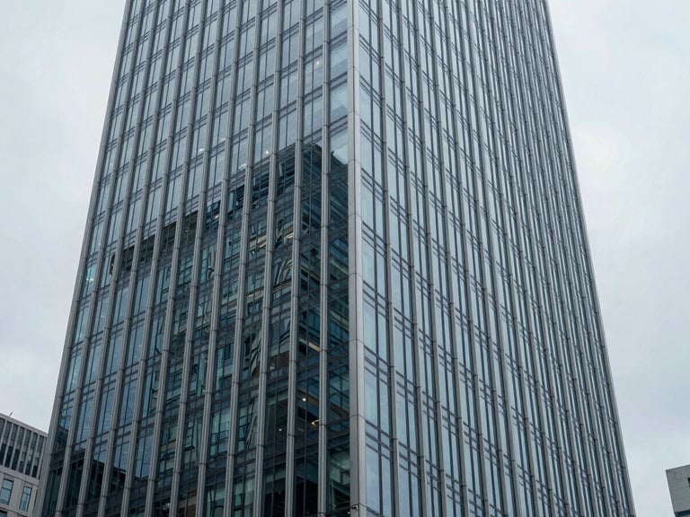 Wide architectural perspective of a modern glass-and-steel skyscraper facade in a global financial district, cool overcast daylight, desaturated blue and slate tones, sharp focus