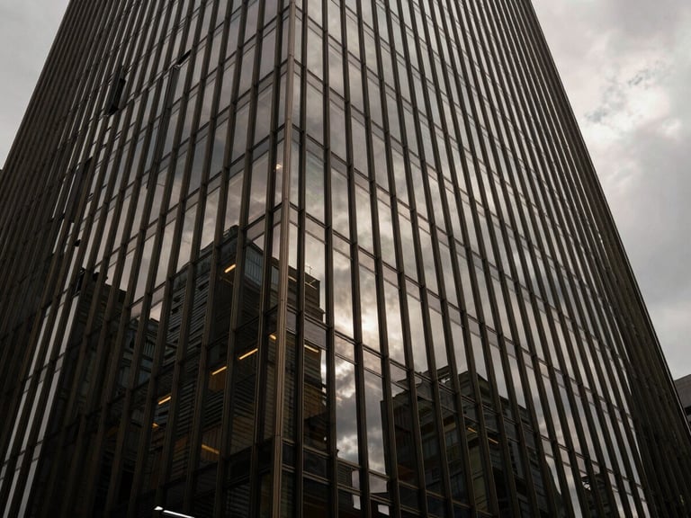 Wide-angle architectural shot of a modern glass skyscraper facade reflecting dramatic overcast skies, sharp shadows, minimalist steel lines, premium architectural photography