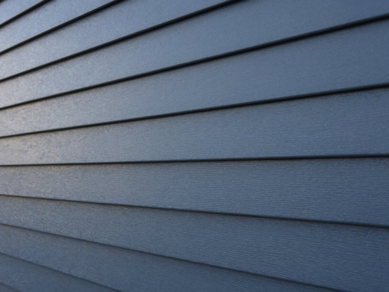 Close-up of pristine modern siding panels in deep slate blue-gray, perfect alignment, soft early morning light, architectural detail, 35mm
