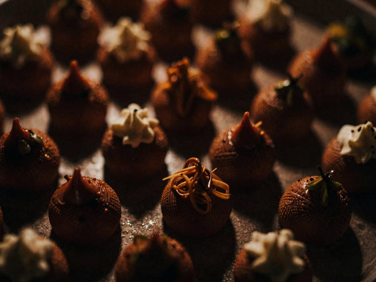 Close-up of a gourmet dish, possibly a dessert, with intricate details, dramatic low-light environment, rich warm tones, high contrast, deep shadows, 35mm film grain.