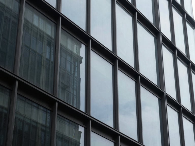 A tight, abstract architectural crop of high-contrast steel and tinted glass facade reflecting cool, diffused daylight, 35mm editorial photography.