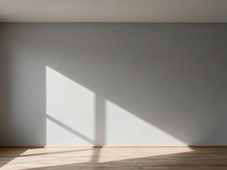 Wide architectural angle of a minimalist Madrid living room, natural daylight raking across a seamless warm grey Mortex wall, shadow play, negative space on the left.