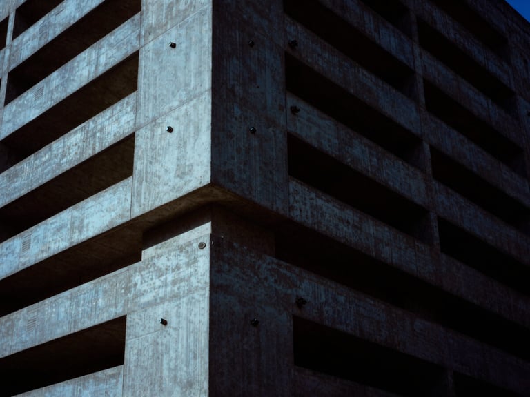 Brutalist concrete monolith with embedded security sensors, low-key, high-contrast, cold blue light, deep shadows, 35mm