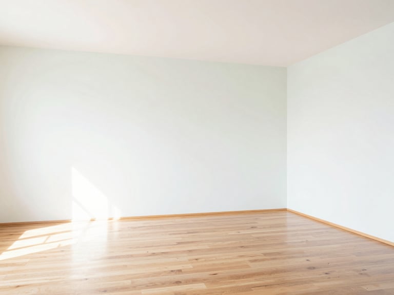 Empty, freshly cleaned room with gleaming hardwood floors and white walls, bright natural light, showing pristine condition, high-key interior.