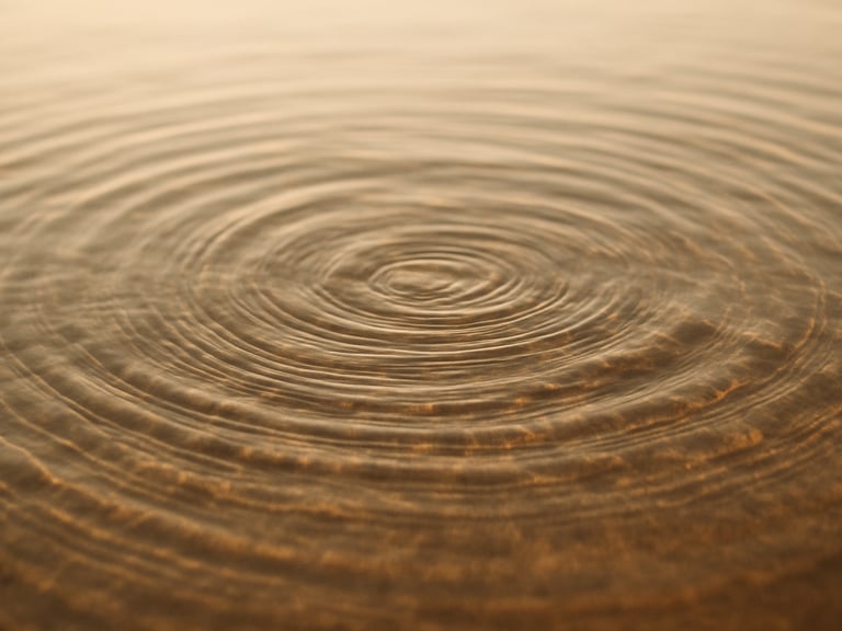 Ripples in clear water under soft golden sunlight, warm natural daylight, minimalist composition