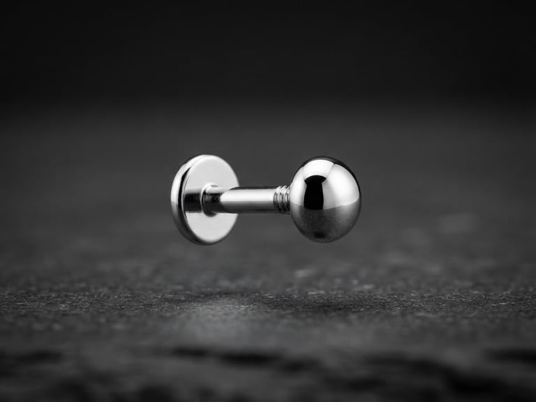 Macro photography of an ASTM F-136 titanium labret with high-polish mirror reflection, floating over a sterile dark stone surface, sharp directional studio light, 3d depth, 85mm