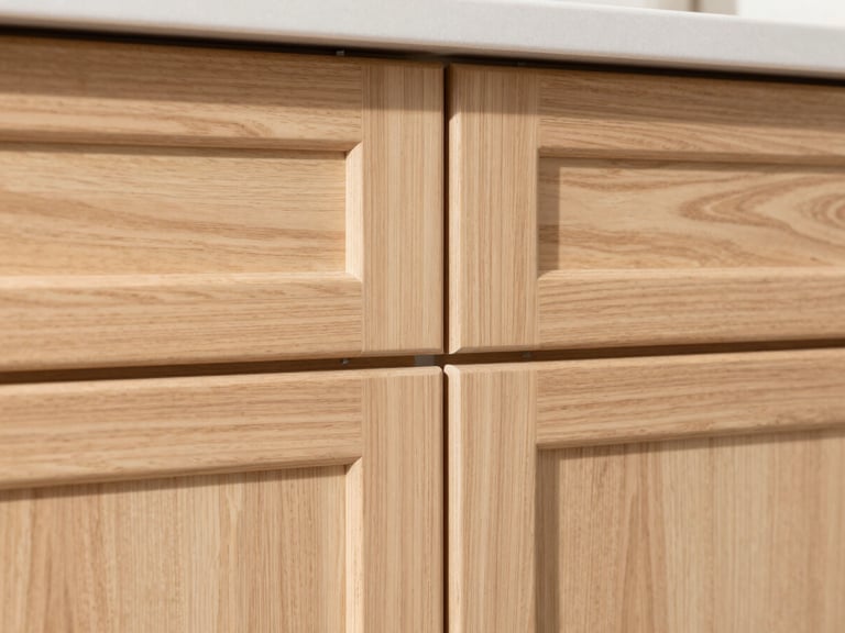 Close-up of newly installed kitchen cabinets, light wood, showing perfect reveals and flush joints under bright natural daylight, crisp focus.
