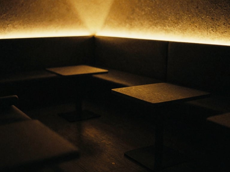 Cozy luxury studio lounge area with soft gold lighting, deep matte black shadows, warm amber glow, comfortable seating, shallow depth of field, 35mm film grain.