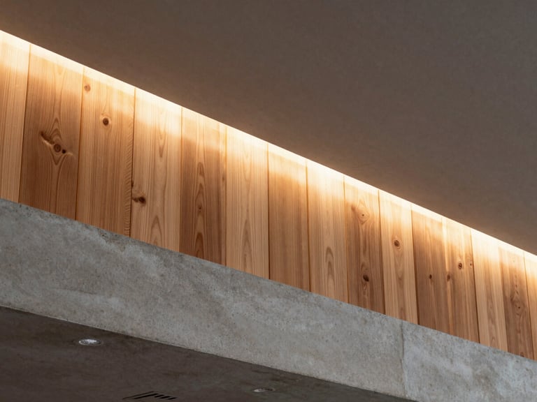 Detalle arquitectónico de un foseado de iluminación en techo de concreto, transición limpia hacia un panel de madera noble de roble, luz cálida difusa.
