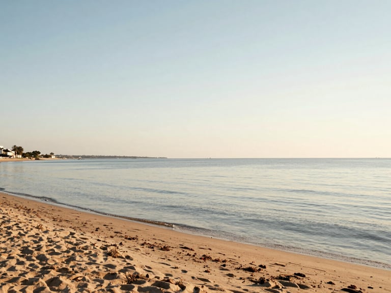 Wide panoramic shot of a quiet sandy beach at the Mar Menor lagoon during soft golden hour, calm shallow water, natural Mediterranean light