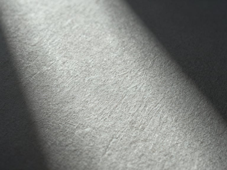 Macro close-up of heavy linen paper texture with subtle blind debossing, cool single-source light from the side, deep elegant shadows.