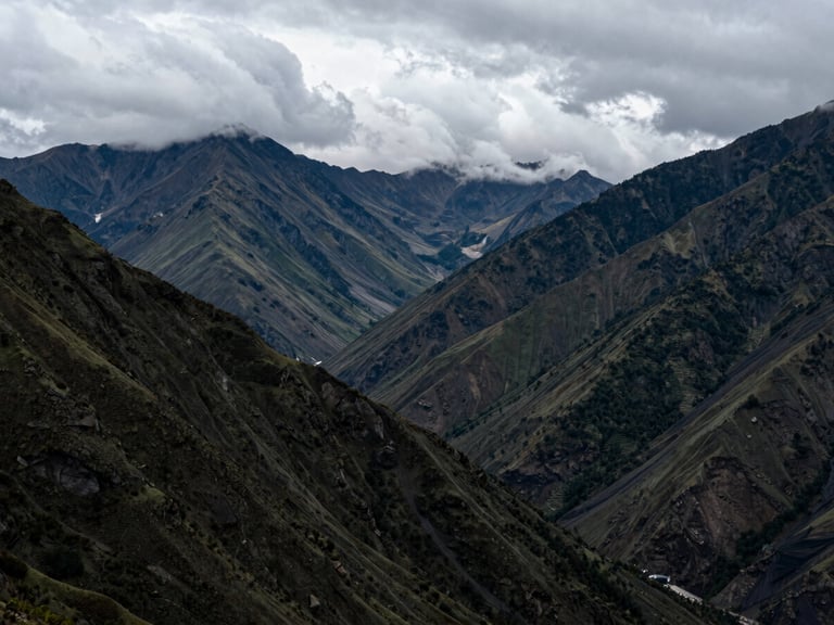 Atmospheric outdoor photography of Machachi valley, cool overcast mountain light, volcanic peaks peeking through clouds, high contrast, 35mm