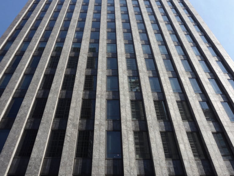 Wide-angle architectural photography of a modern skyscraper facade with dark ceramic panels, sharp daylight, high contrast