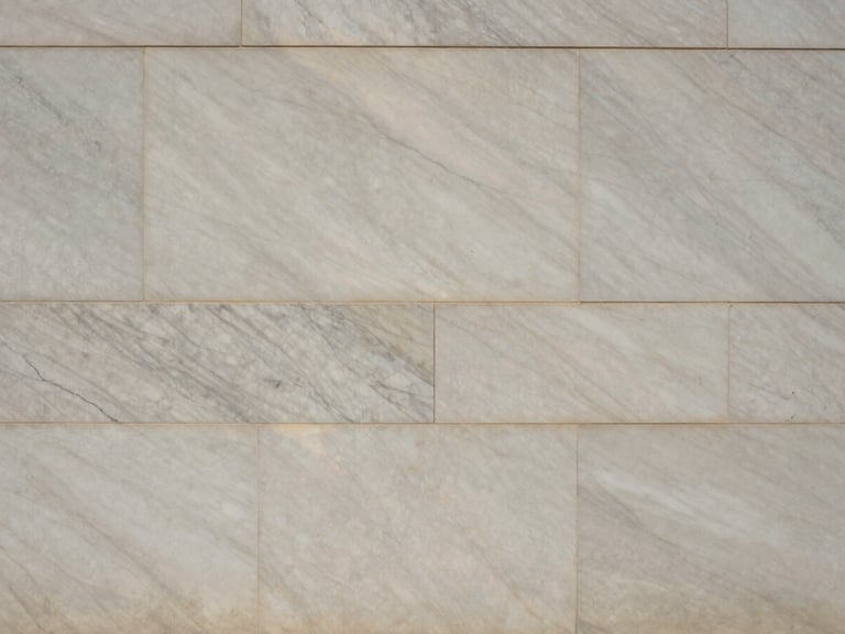Straight-on architectural elevation of a finished marble wall, showcasing continuous vein alignment across multiple panels under natural raking light.
