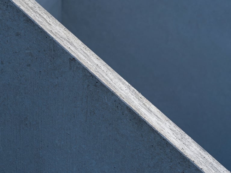 Ultra-tight abstract macro detail of raw concrete texture, a sharp diagonal shadow cutting across the frame, cold clinical blue hour lighting, high-contrast architectural photography, precise geometric lines.
