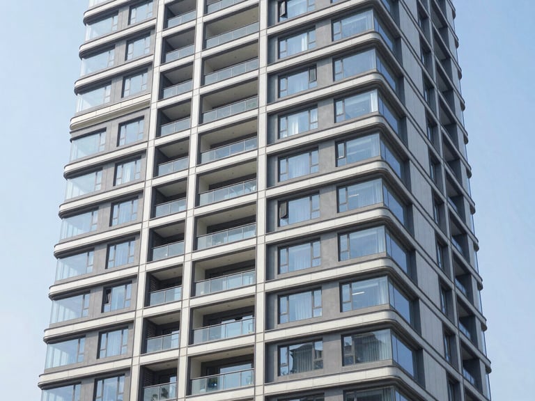 Wide architectural shot of a modern residential tower with clean geometric lines, bright natural daylight, 35mm lens