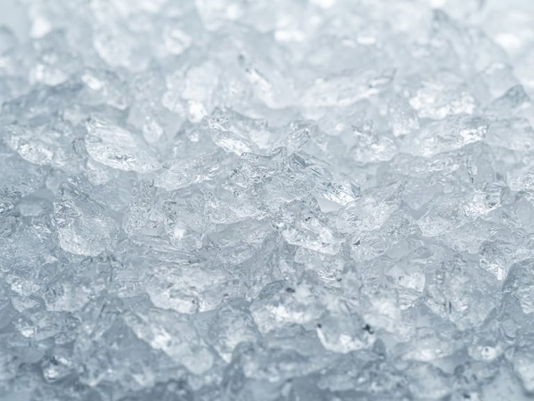 Macro photograph of clean, dense flake ice glistening under cool clinical light, sharp focus on ice textures, 35mm