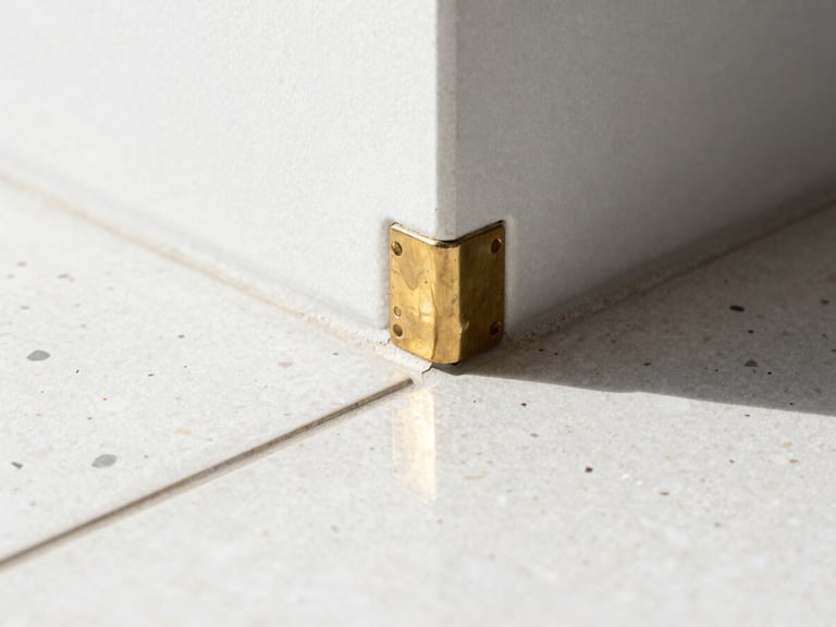 Macro architectural photography of a pristine raw brass joint meeting polished terrazzo, bright natural daylight, clean reflections