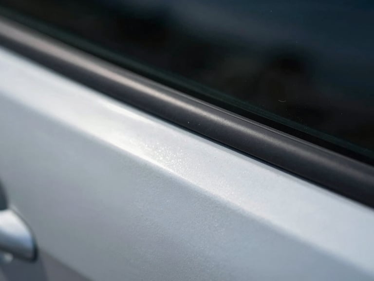 Extreme close-up macro shot of a car door panel dent edge under cool overcast daylight, the ridge of the dent casting a sharp shadow line across bare steel, no paint damage visible, technical documentation framing