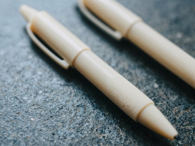 Extreme close-up of fine tactile ivory stationery on a dark stone desk, soft morning daylight, cool shadows, editorial film photography.