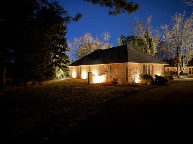 Residential exterior house landscape lighting illuminating a brick home at night.