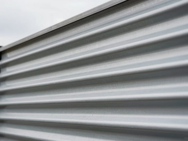 Macro close-up of industrial corrugated steel siding, clean lines, diffused overcast daylight.