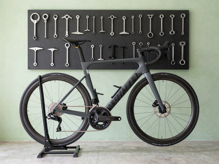 Side view of a clean, organized bicycle repair stand, a carbon frame road bike mounted, tools arranged neatly on a magnetic strip in the background