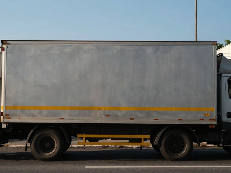 Urban road in Sao Paulo, an empty cargo truck with its back door closed, clear morning daylight, eye-level.