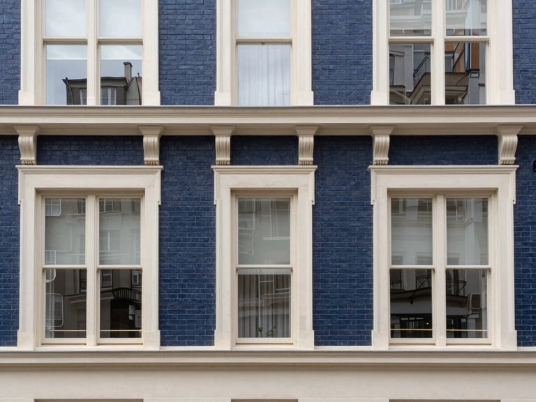 Straight-on architectural photograph of a historic brick apartment building facade with large sash windows, soft overcast daylight, clean lines, sharp focus