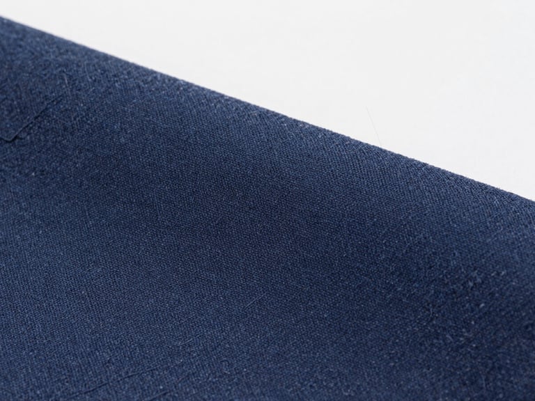 High-magnification macro shot of deep navy dyed acetate tricot fabric, showing detailed fiber weave, clean industrial studio lighting