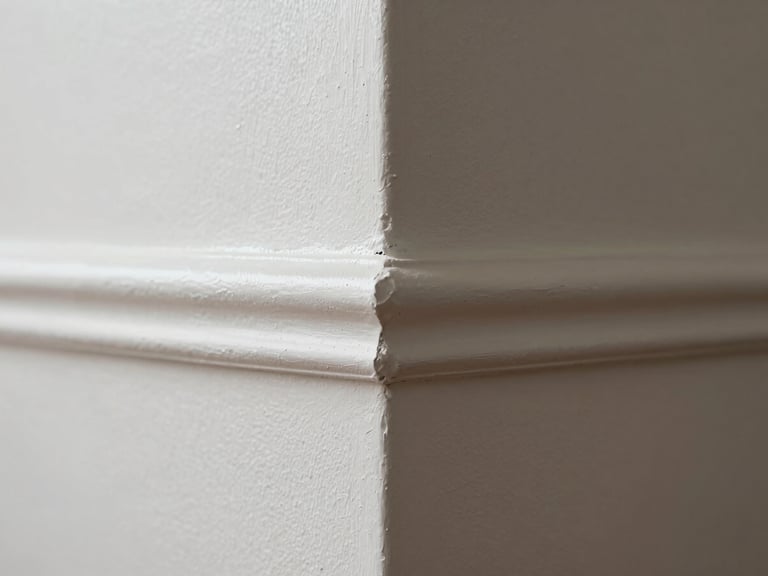 Tight close-up of a freshly painted wall corner showing a crisp paint edge where two colors meet at the trim, even sheen visible under natural window light, no smudges or bleeds