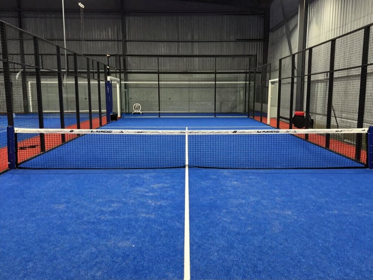 Close-up of a padel court net with red accents, pristine court lines visible under bright sun