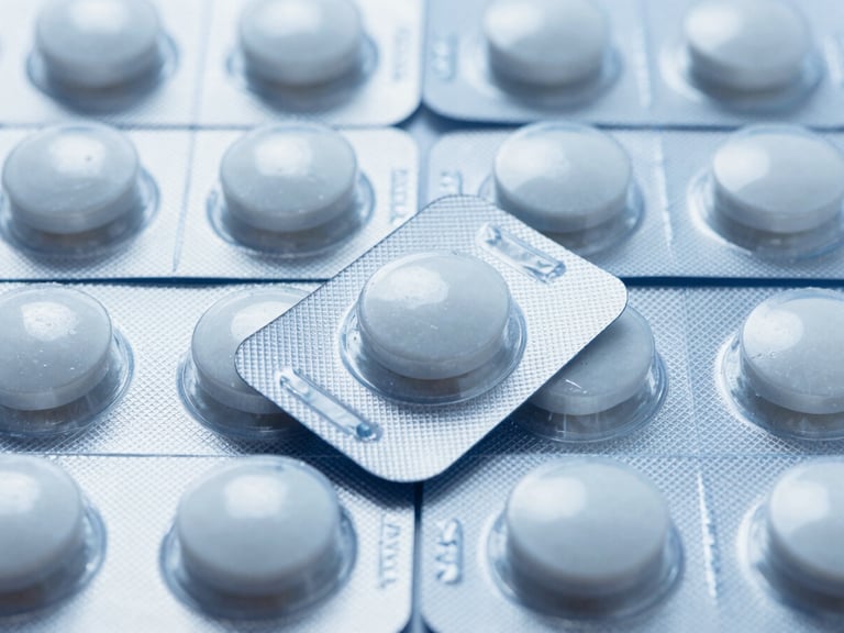Macro shot of batch-certified pharmaceutical blister packs arranged in a precise geometric grid under cool clinical laboratory light, showcasing molecular precision and sterile packaging.