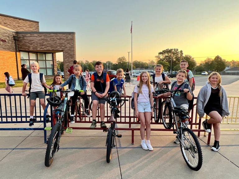 Group of kids on bikes parked at a bike rack posing for the camera