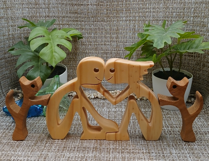 a wood figurine of a loving couple and their two pets