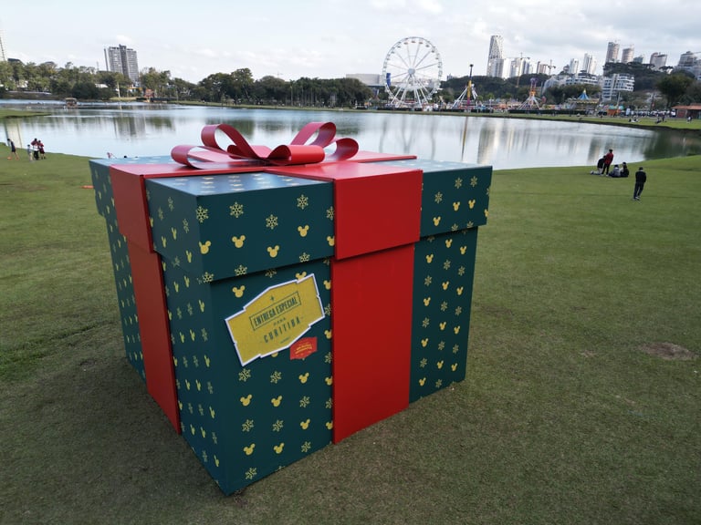 caixa de presente verde com laço vermelho e logo do mickey em um gramado verde em Curitiba