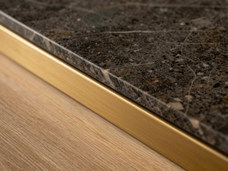 Close-up macro shot of premium materials, a slab of dark marble meeting a brushed brass trim and raw oak floor, warm lighting.