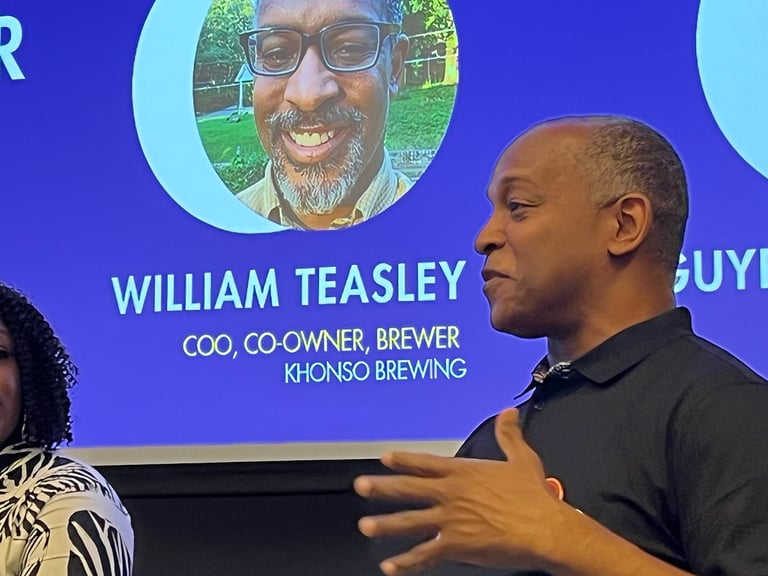 William Teasley of Khonso Brewing speaking at a business conference with his digital profile displayed behind him.
