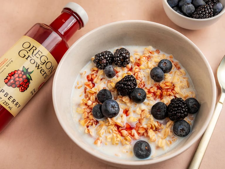 a bowl of cereal with berries and a bottle of syrup