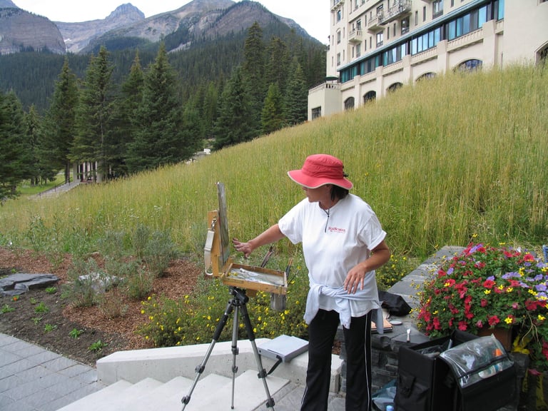 an artist painting outside with a mountain range in the background