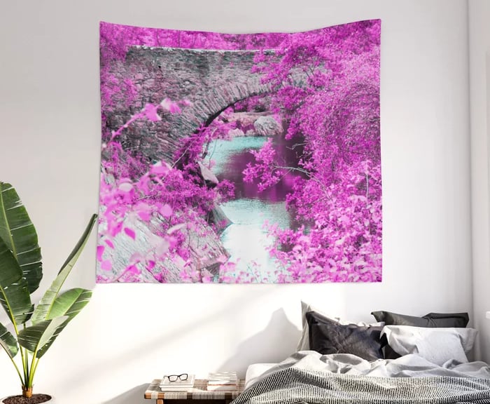 Wall tapestry of fantasy bridge hanging on wall with bed underneath this.