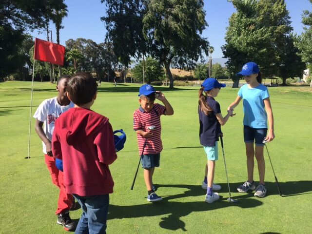 Enhancing Forward Action Inc. image of a group children on a golf course shacking hands