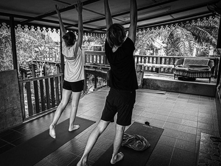 A man and woman practising yoga on a wooden veranda