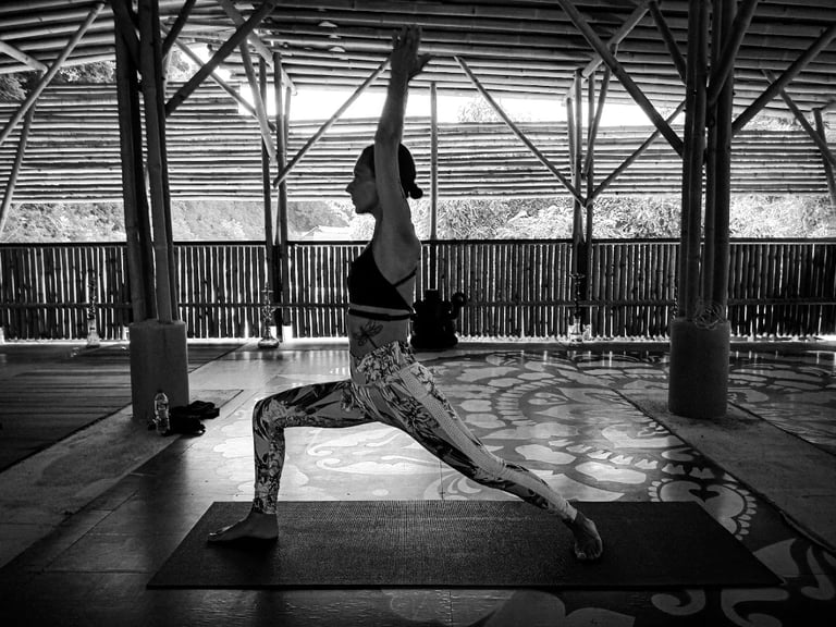 A woman in Warrior One pose in Yoga practice at the Bamboo Cottage Langkawi